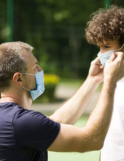 Health care concept. Father putting protective face mask on his child against infectious diseases and flu