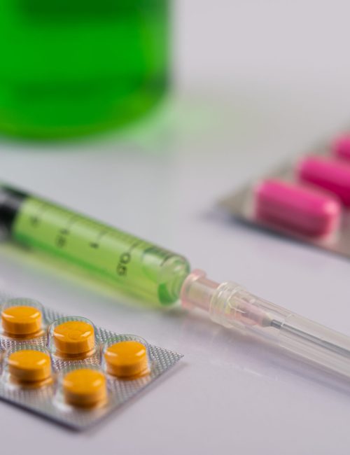 Medicine panels, syringes and beakers are placed on the floor. Selective focus.